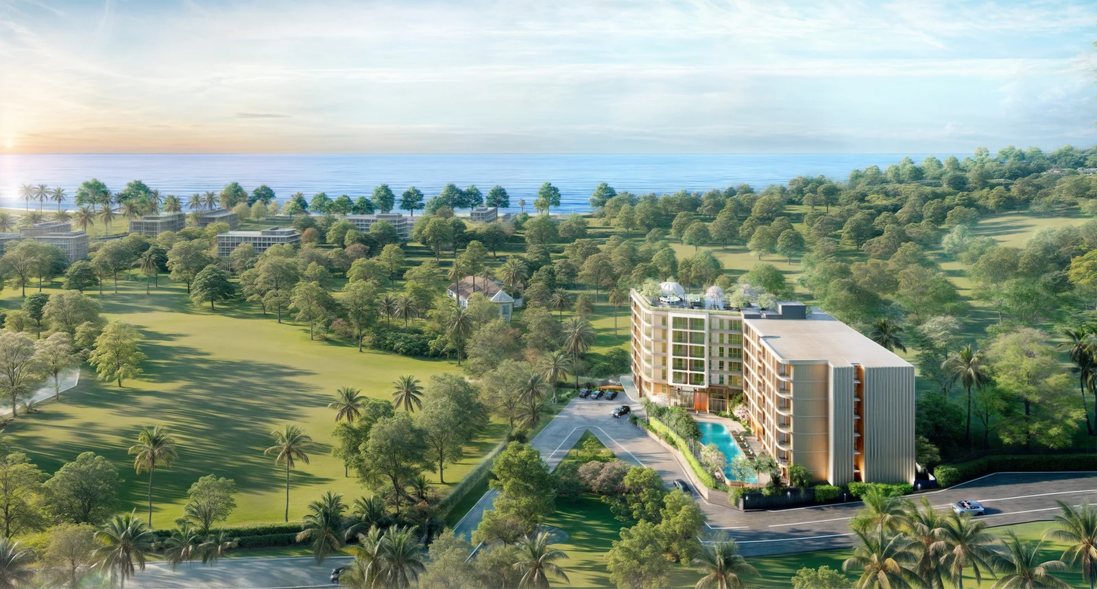 Wide aerial: the building among forested hills with the sea beyond